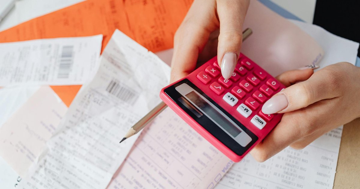 Factura de la luz junto a una calculadora y un enchufe sobre una mesa